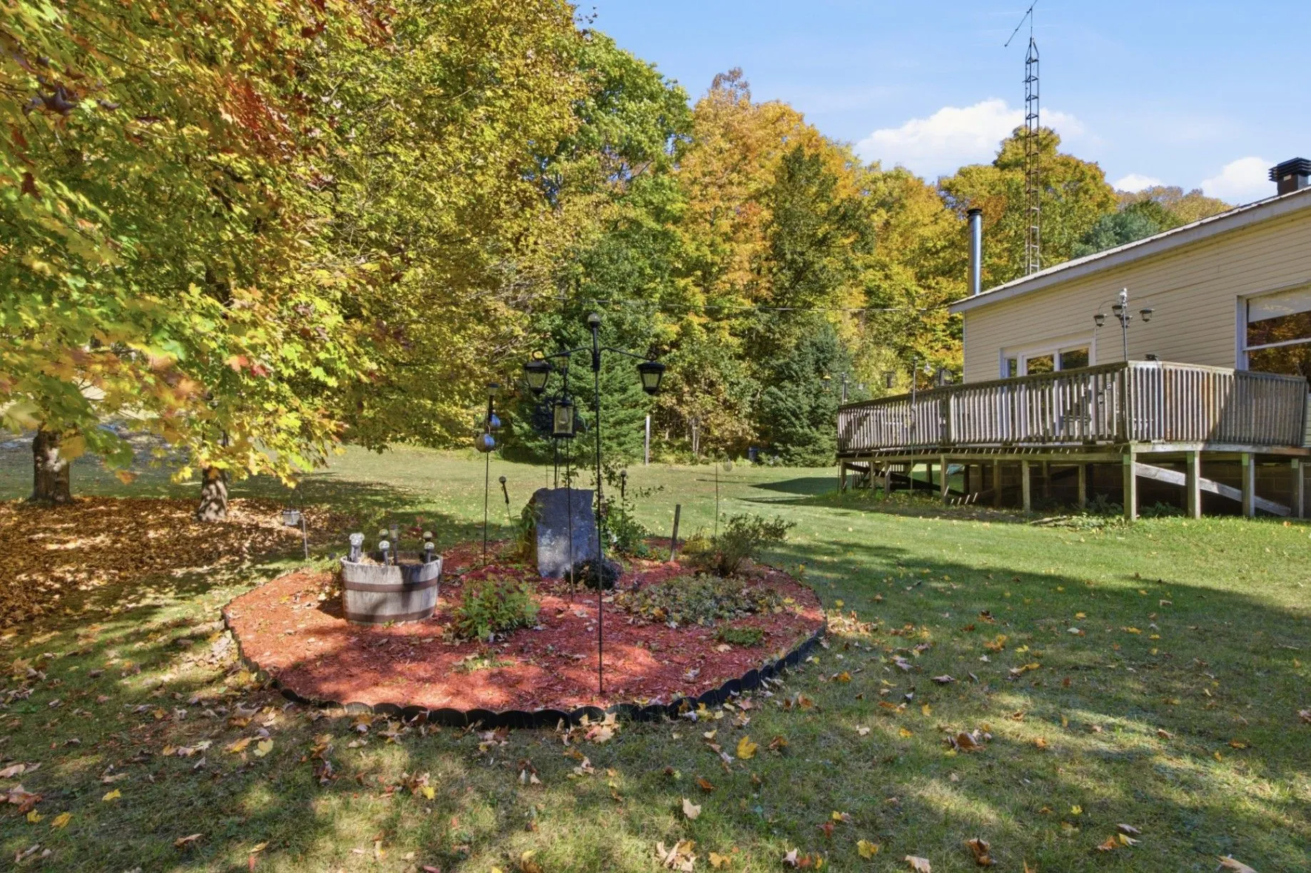 3192 Matawatchan Rd, Greater Madawaska — level backyard with garden bed and wraparound deck